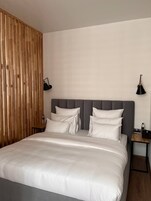Een slaapkamer met een groot bed, twee nachtkastjes en een houten scheidingswand.
