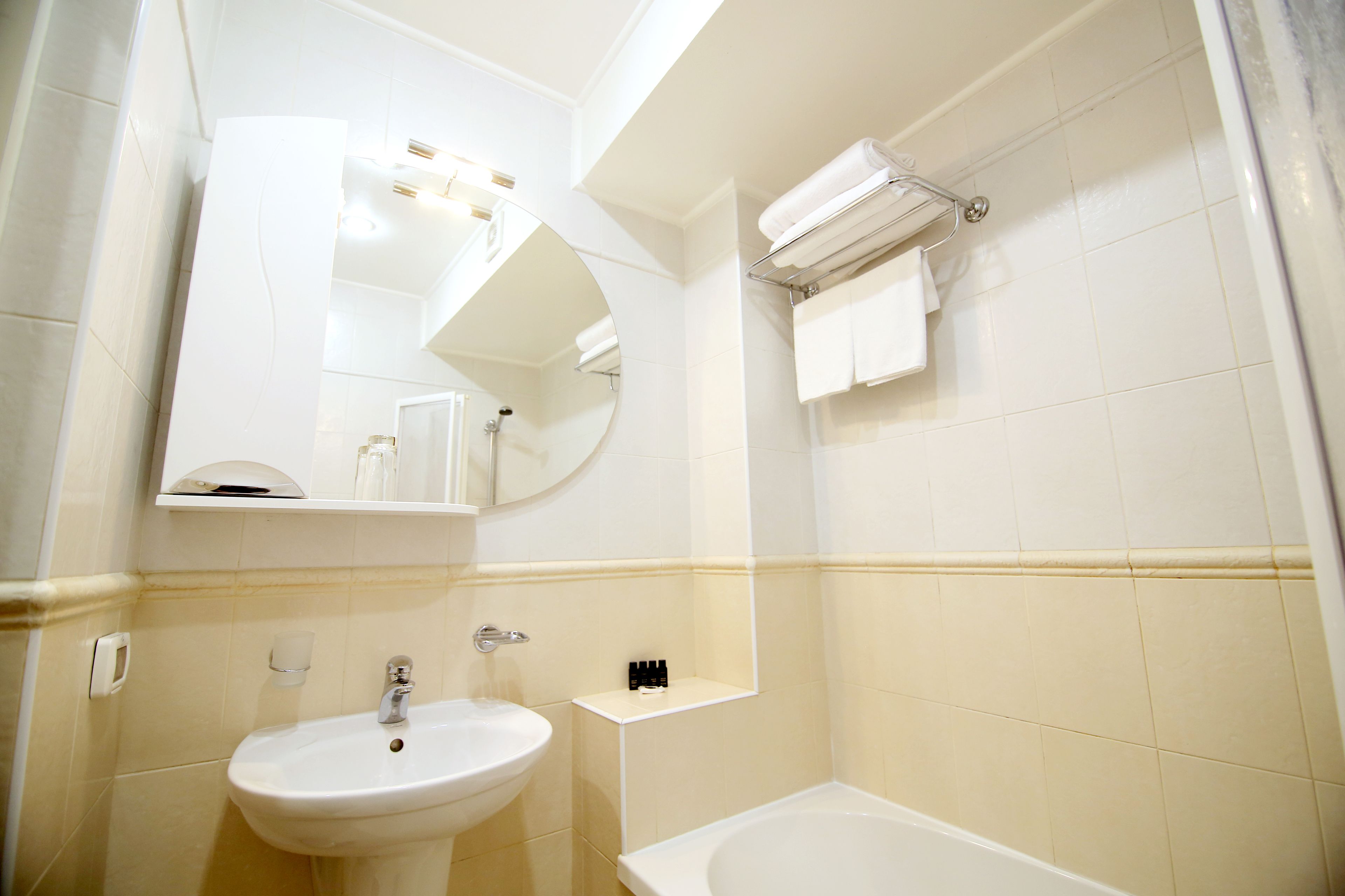 A bathroom with a sink, mirror, and bathtub.