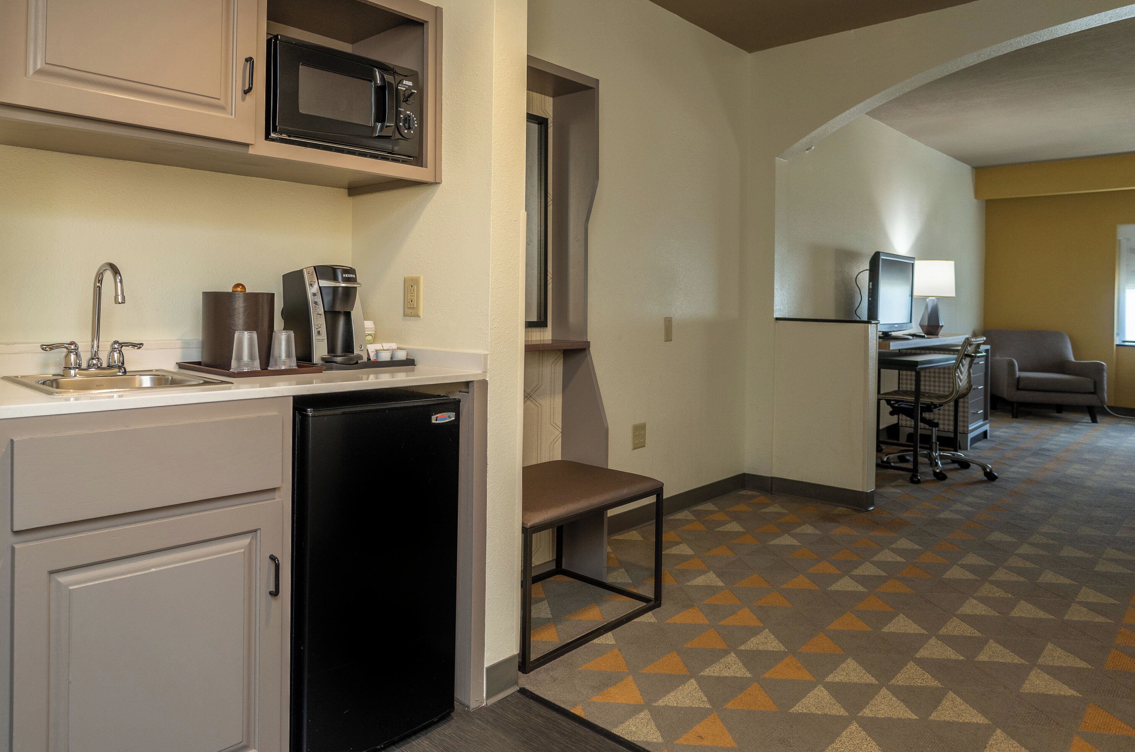 A compact kitchenette with a microwave, coffee maker, and a dishwasher.