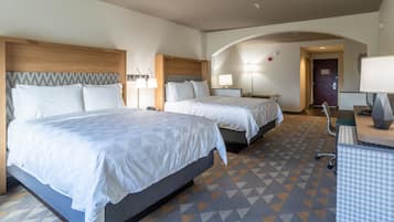 Ein Hotelzimmer mit zwei Betten, einem Schreibtisch, einem Stuhl und einer Lampe.