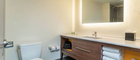 A bathroom with a toilet, sink, mirror, towel rack, and a hair dryer.