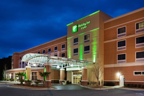 A Holiday Inn & Suites hotel with a glass entrance and a brick facade.