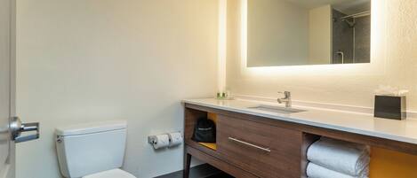 A modern bathroom with a toilet, a sink, a mirror, and a towel rack.
