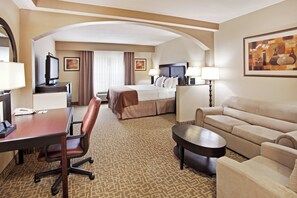 A hotel room with a bed, a desk, a chair, a sofa, and a coffee table. - Holiday Inn Hotel & Suites Beaufort at Highway 21 by IHG (Beaufort)