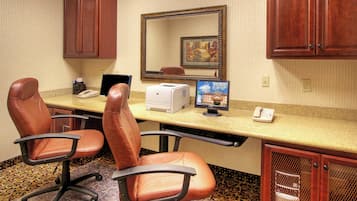 A conference room with two leather chairs, a desktop computer, a printer, and a telephone.