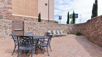 An outdoor patio with a stone wall, a table with chairs, and a view of a motel sign in the background.