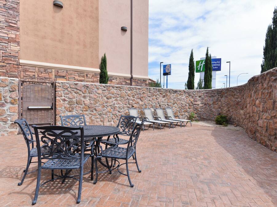 An outdoor patio with a stone wall, a table with chairs, and a view of a motel sign in the background.