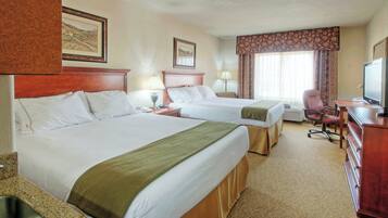 A hotel room with two beds, a desk with a television, and a chair.