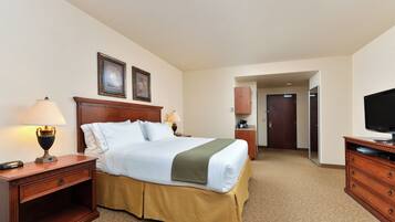 A hotel room with a large bed, two bedside tables with lamps, a television, and a wardrobe.