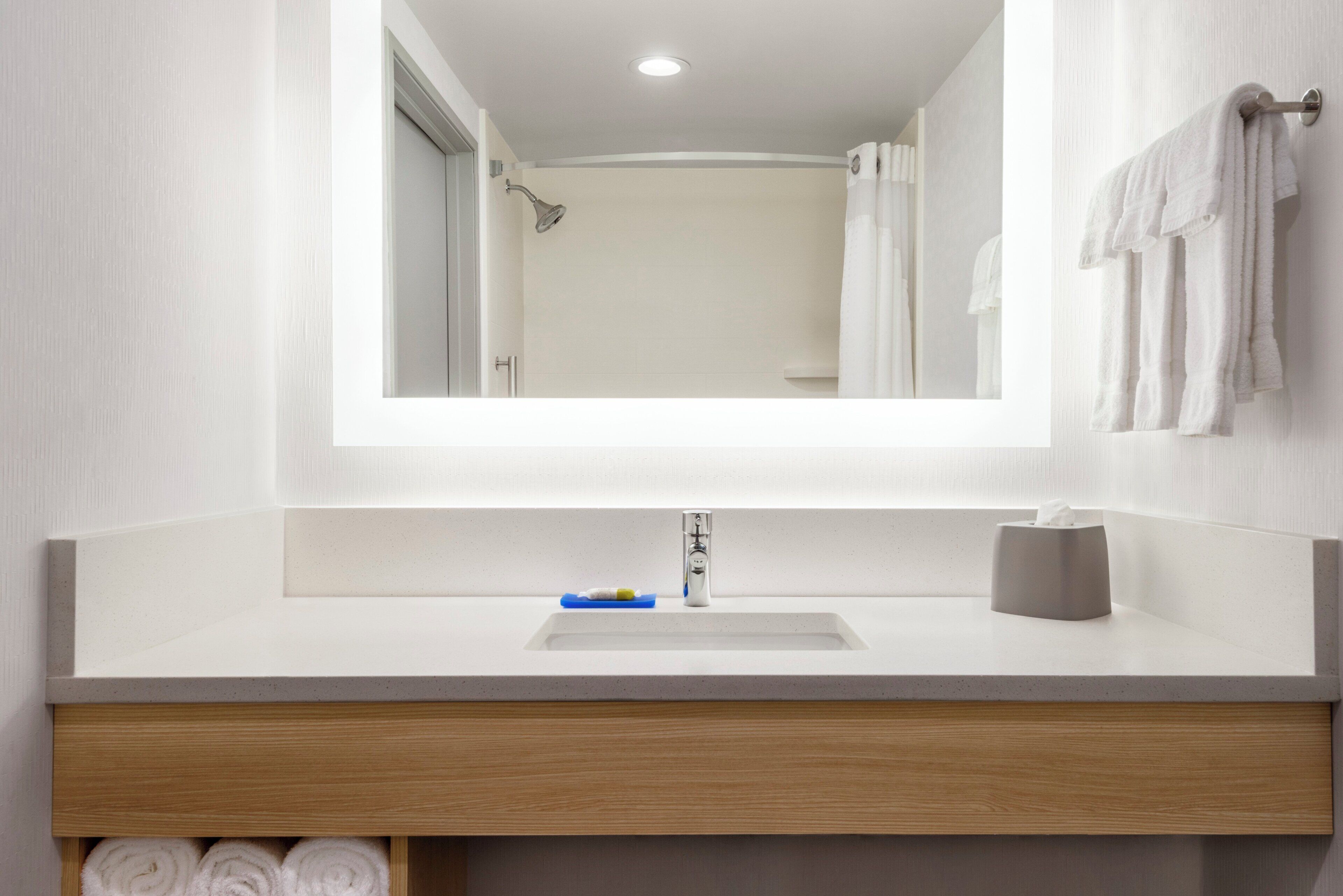 A modern bathroom with a large mirror, a sink, and a towel rack.