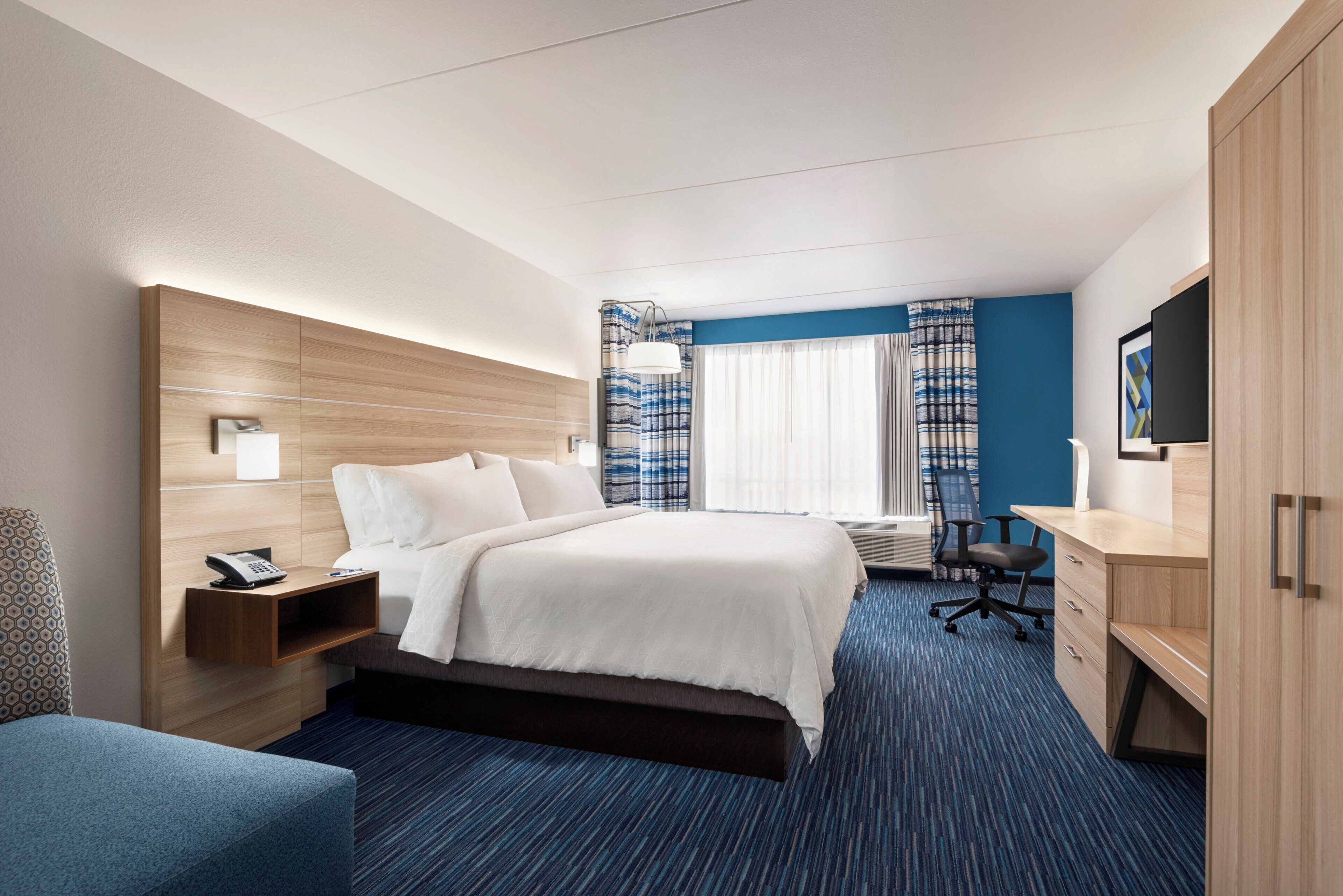 Una habitación de hotel con cama, escritorio, silla y armario.