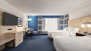 Hotelkamer met een bureau, twee bedden, een stoel, een flatscreen-tv en een raam met gordijnen.