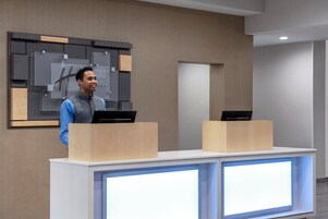 Una recepción con dos estaciones de trabajo de computadoras, un diseño moderno de pared y una paleta de colores neutros.