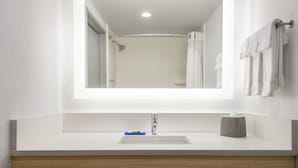 Een moderne badkamer met een witte wastafel, een spiegel en een handdoekhouder.