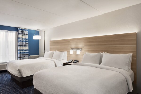 A hotel room with two beds, a nightstand with a phone, a wall-mounted light, and a window with curtains. - Holiday Inn Express Dumfries by IHG (Dumfries)