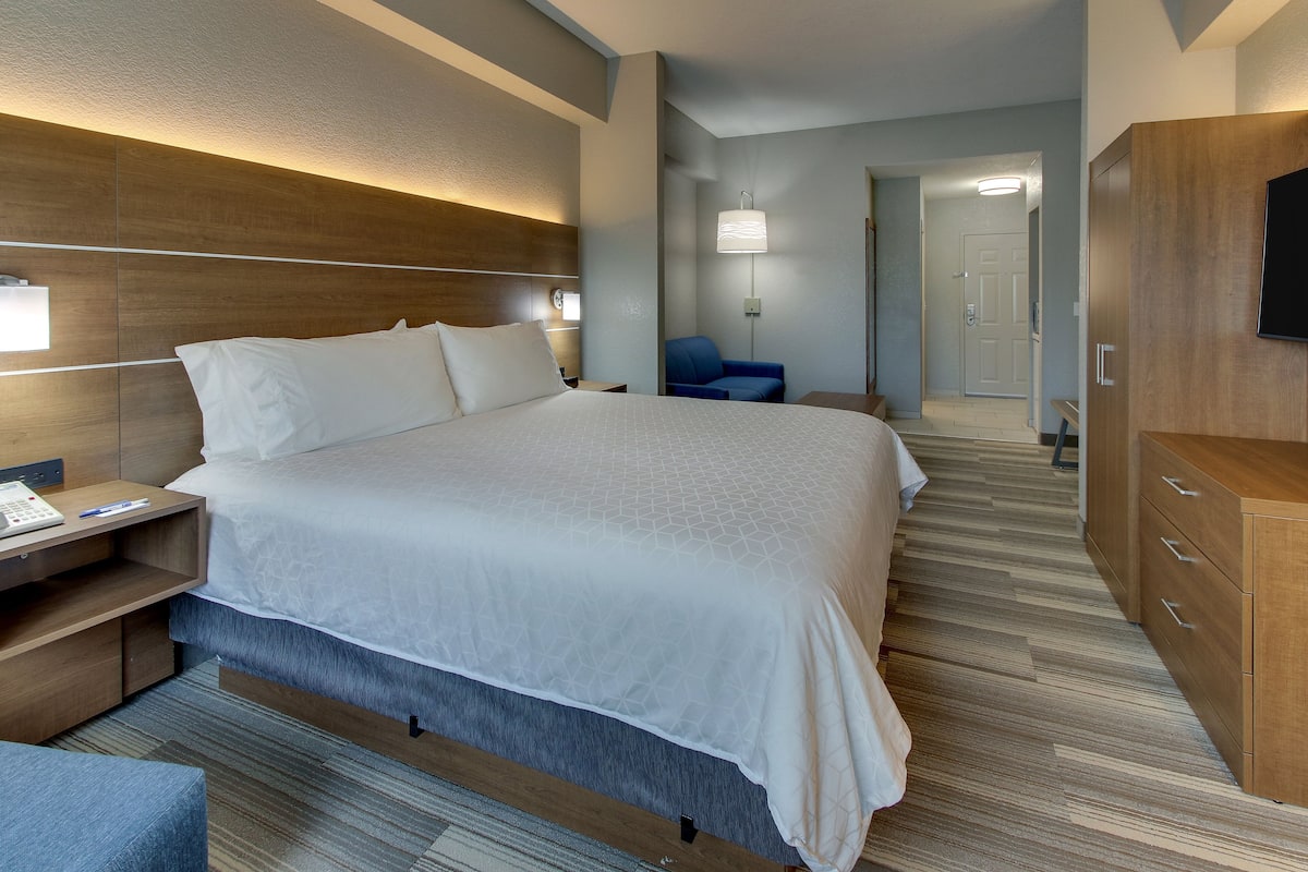 Habitación de hotel con una cama grande, mesitas de noche, un escritorio, una silla, un armario y un televisor.