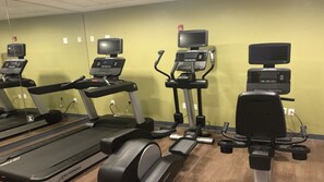 Een fitnessruimte met loopbanden, elliptische trainers en hometrainers, voorzien van digitale schermen en hartslagmeters.