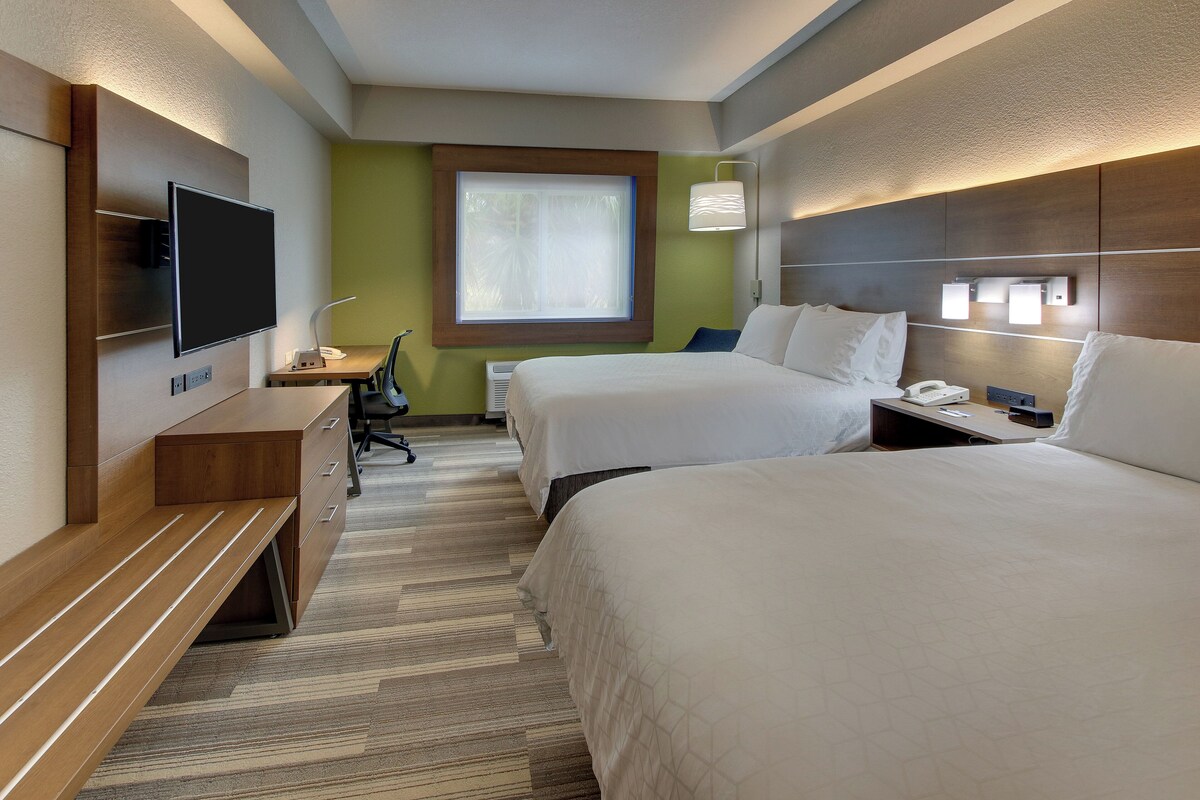 Een hotelkamer met twee bedden, een bureau, een stoel, een flatscreen-tv en een raam.