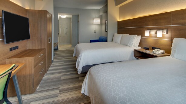 A hotel room with two beds, a desk, a TV, and a bathroom visible in the background. - Holiday Inn Express & Suites West Palm Beach Metrocentre by IHG (West Palm Beach)