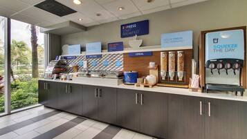 A breakfast bar with various food options and a sign that reads 'SQUEEZE THE DAY'.