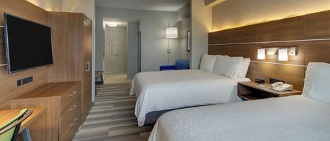 A hotel room with two beds, a desk, a TV, and a bathroom visible in the background.