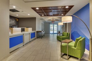 Eine Hotelhalle mit Rezeption, Sitzgelegenheiten und Blick ins Freie.