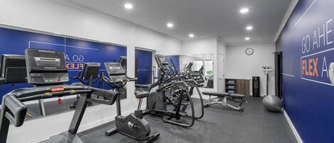 A modern gym with treadmills, ellipticals, and a large exercise ball.