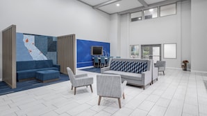 Un vestíbulo amplio con una decoración azul y blanca, un mapa grande en la pared y un área de descanso con sofás y sillones.