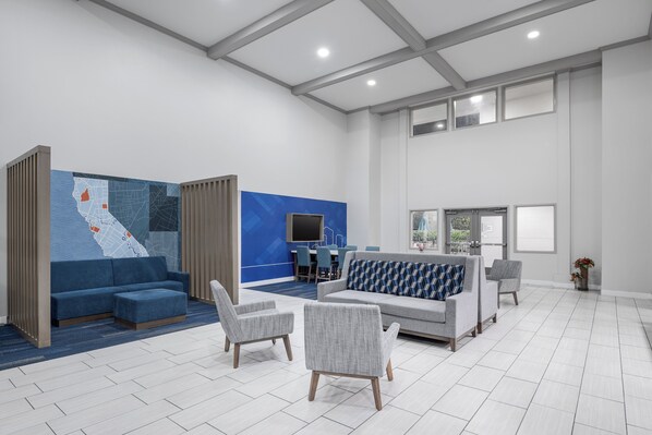 Un'ampia hall con una combinazione di colori blu e bianco, una grande mappa appesa al muro e un'area relax con divani e poltrone.