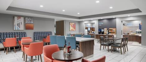 A modern hotel lobby with seating areas, a bar, and a coffee station.