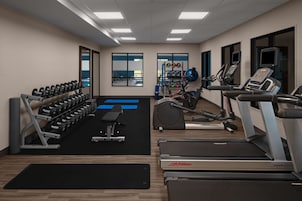 Un gimnasio con mancuernas, cintas de correr y equipamiento de ejercicio.