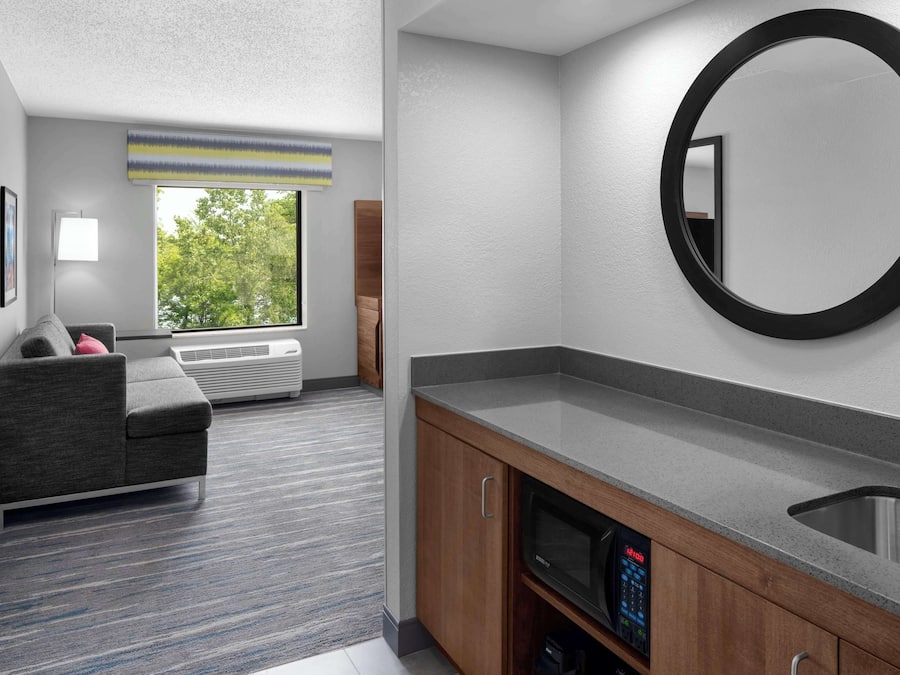 A modern bathroom with a grey countertop, a round mirror, and a built-in sink.
