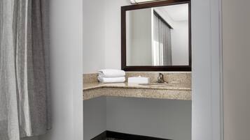 A bathroom with a granite countertop, a sink, a mirror, and a towel rack.
