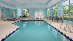 An indoor swimming pool with clear blue water, surrounded by lounge chairs and a table. - SpringHill Suites by Marriott Portland Vancouver (Vancouver)