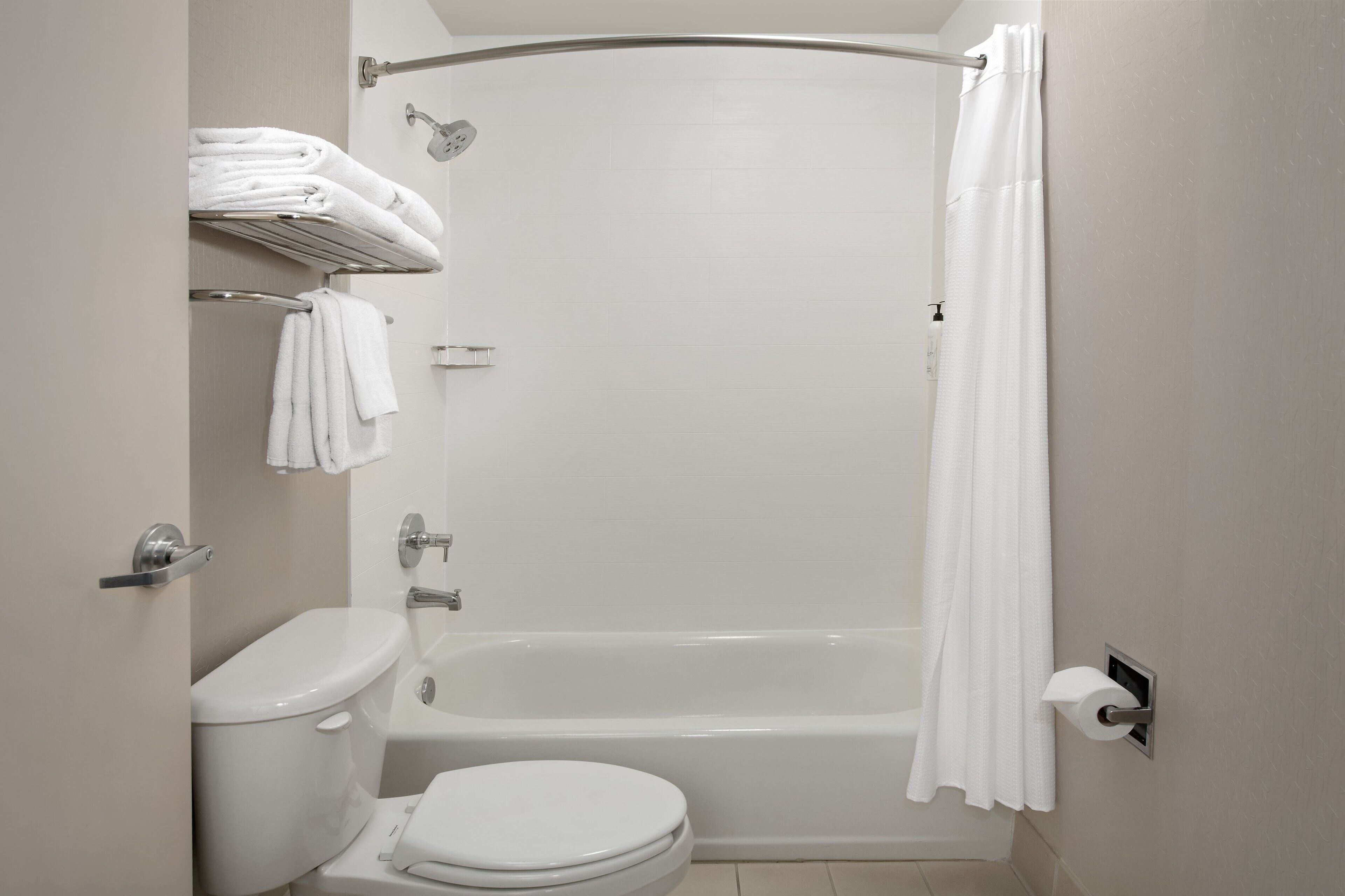 A modern bathroom with a bathtub, toilet, and towel rack.