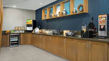 A modern kitchen with wooden cabinets, a built-in coffee machine, and a self-serve beverage station.