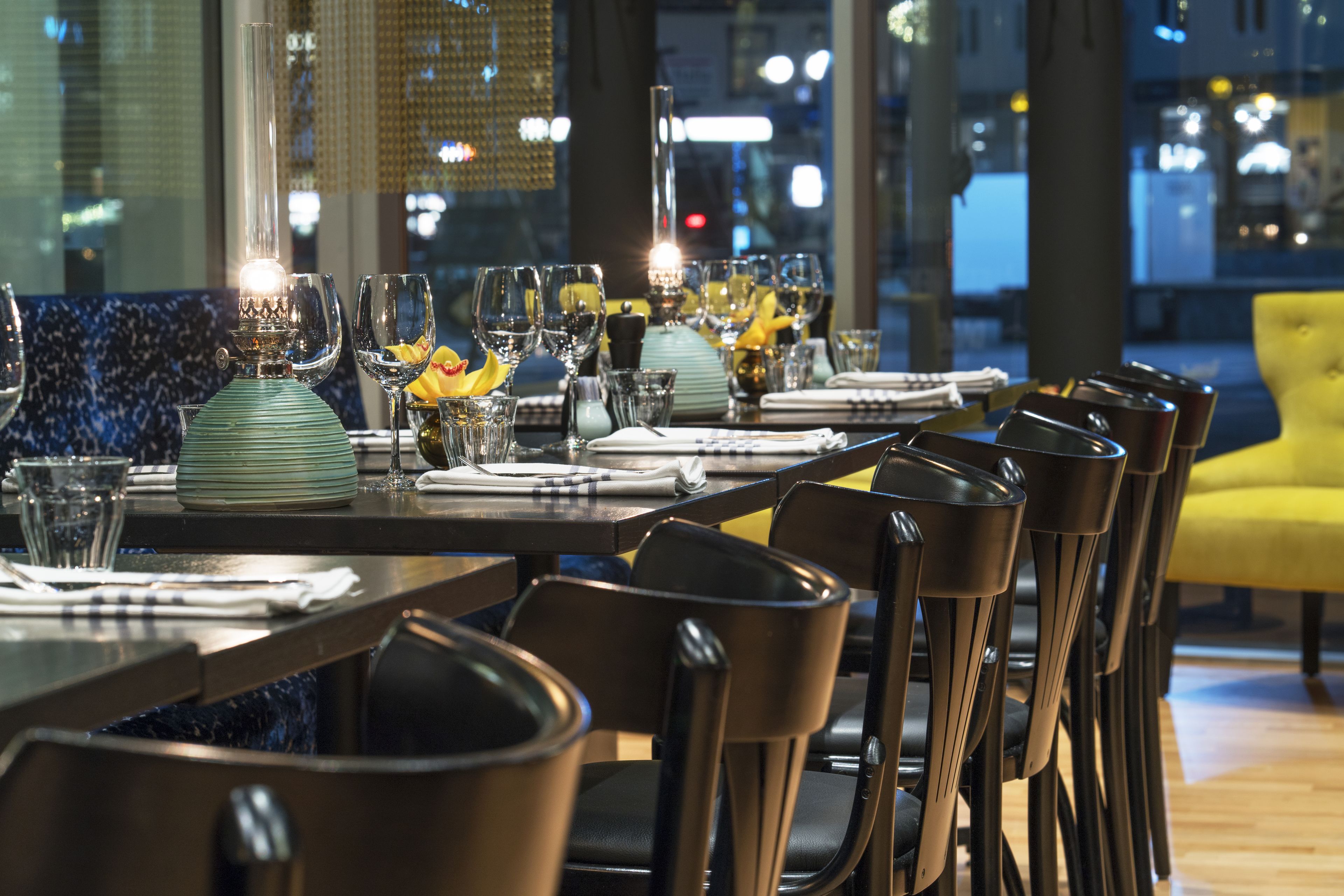 Een restaurant met gedekte tafels, stoelen en een decoratieve lamp.