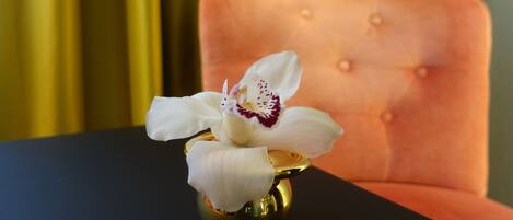 Une orchidée blanche dans un vase doré, posée sur une table noire.