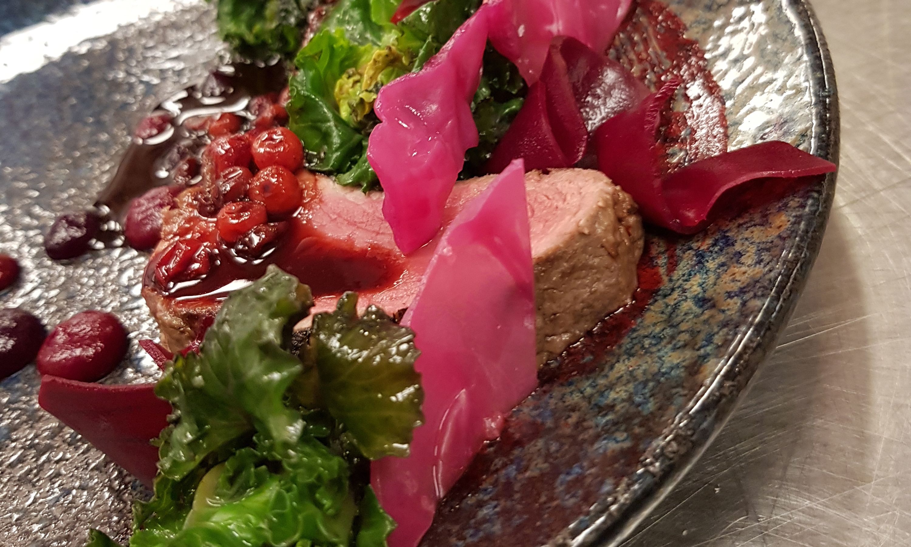 Primer plano de un plato con carne, verduras y salsa.