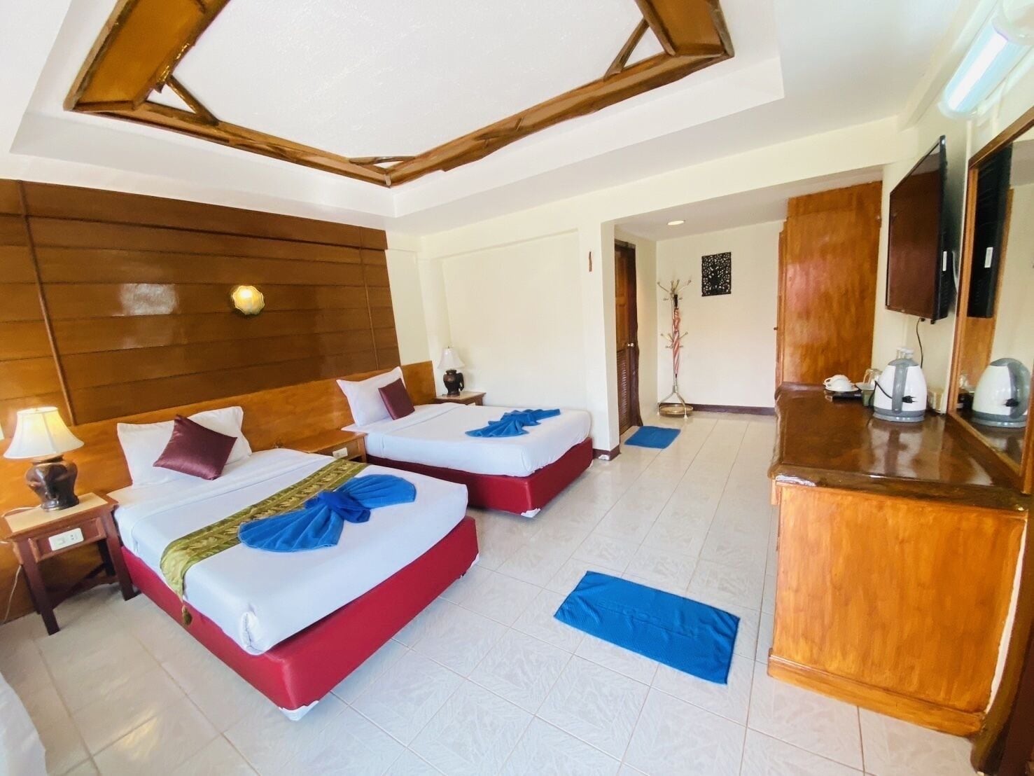 Habitación de hotel con dos camas, cabeceros de madera, un minibar y una televisión.