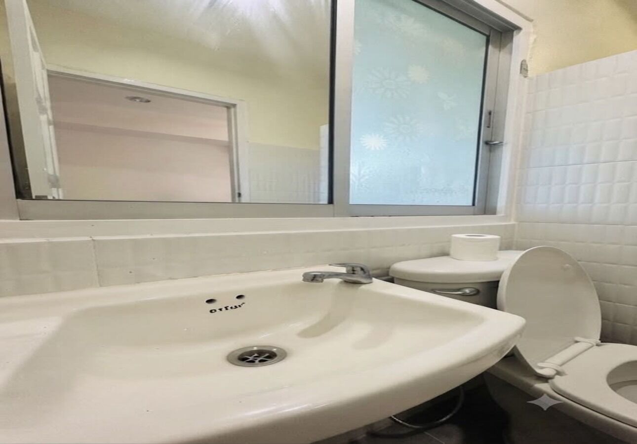Un baño con lavamanos, inodoro y ventana.