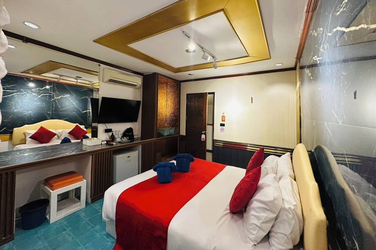 A hotel room with a bed, a desk, a television, and a mirror.