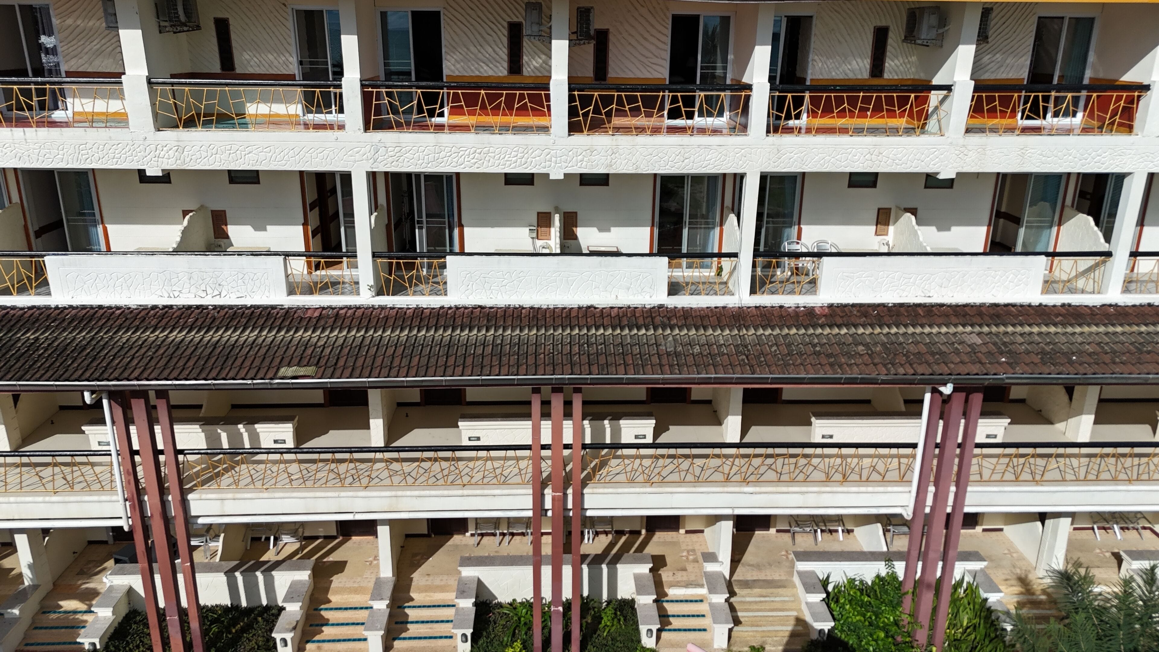 A multi-story building with a tiled roof, balconies with metal railings, and a central staircase.