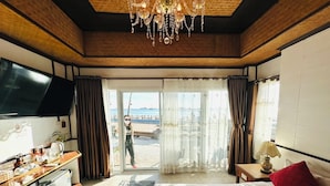 Ein Hotelzimmer mit Bett, Schreibtisch, Fernseher, einer Kristallleuchter und Blick auf den Strand.