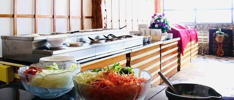 A kitchen with a stove, a buffet table with various food items, and a potted plant.