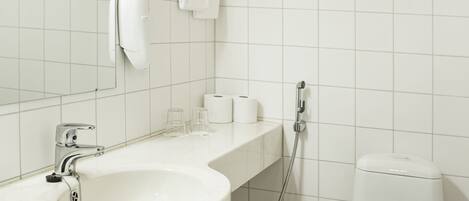 A bathroom with a white sink, a mirror, a toilet, and a shower.