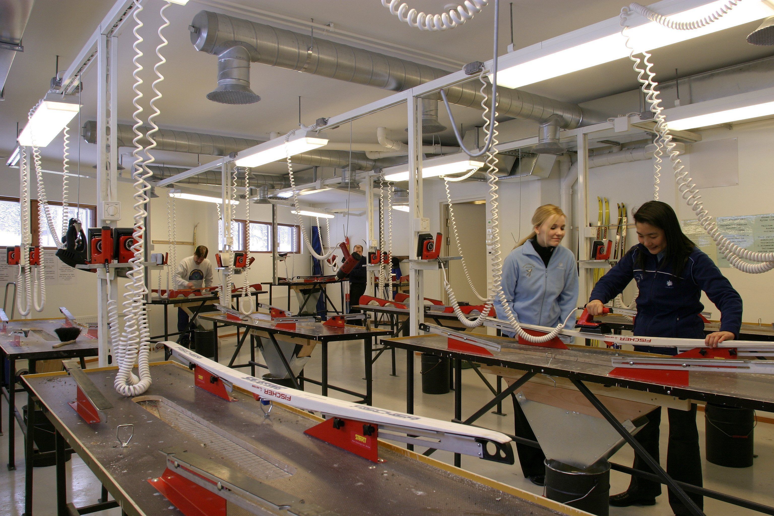 Un atelier avec des tables, des outils et des personnes qui travaillent.