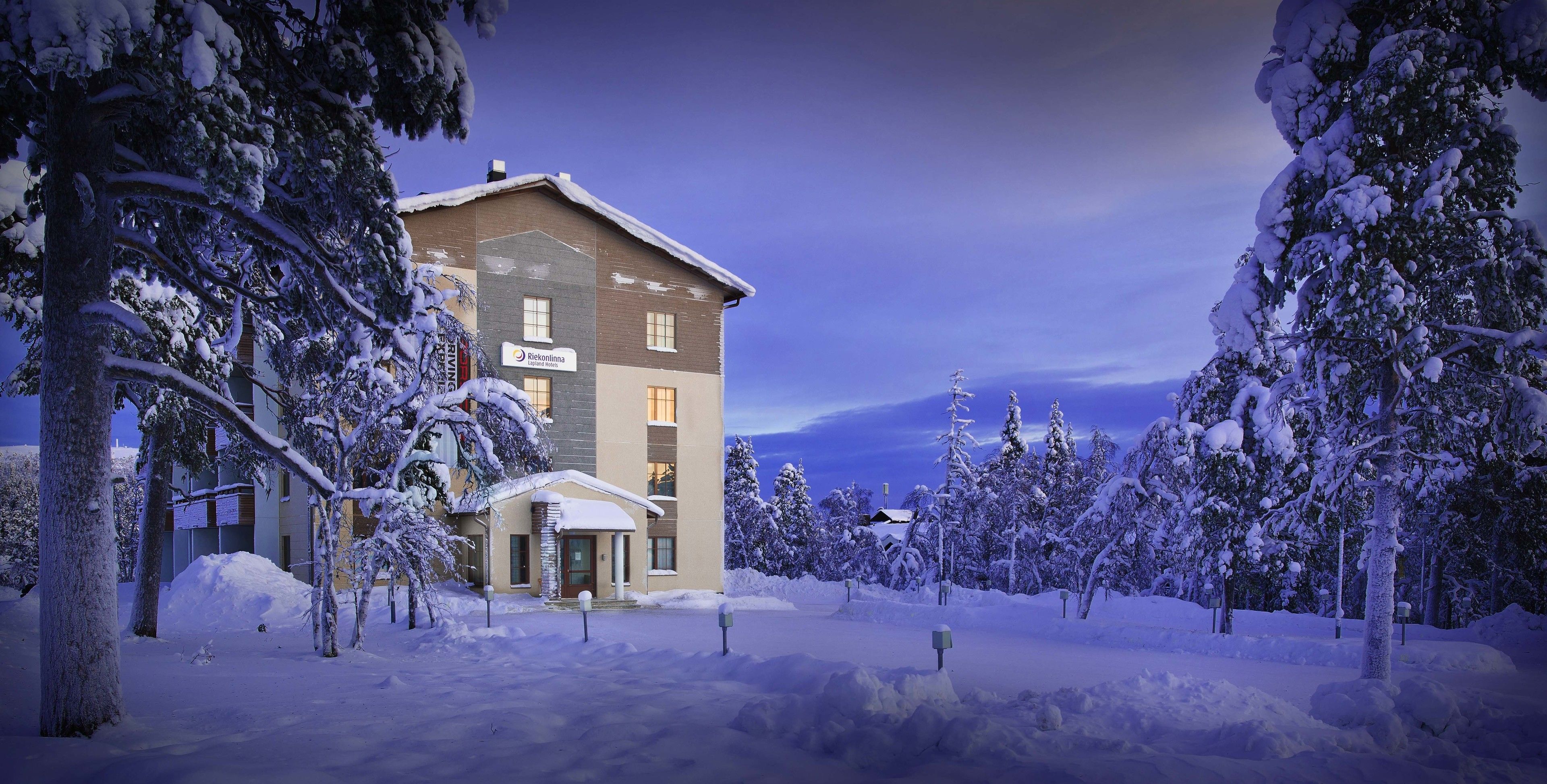 A hotel with a stone facade, multiple windows, and a snow-covered landscape.