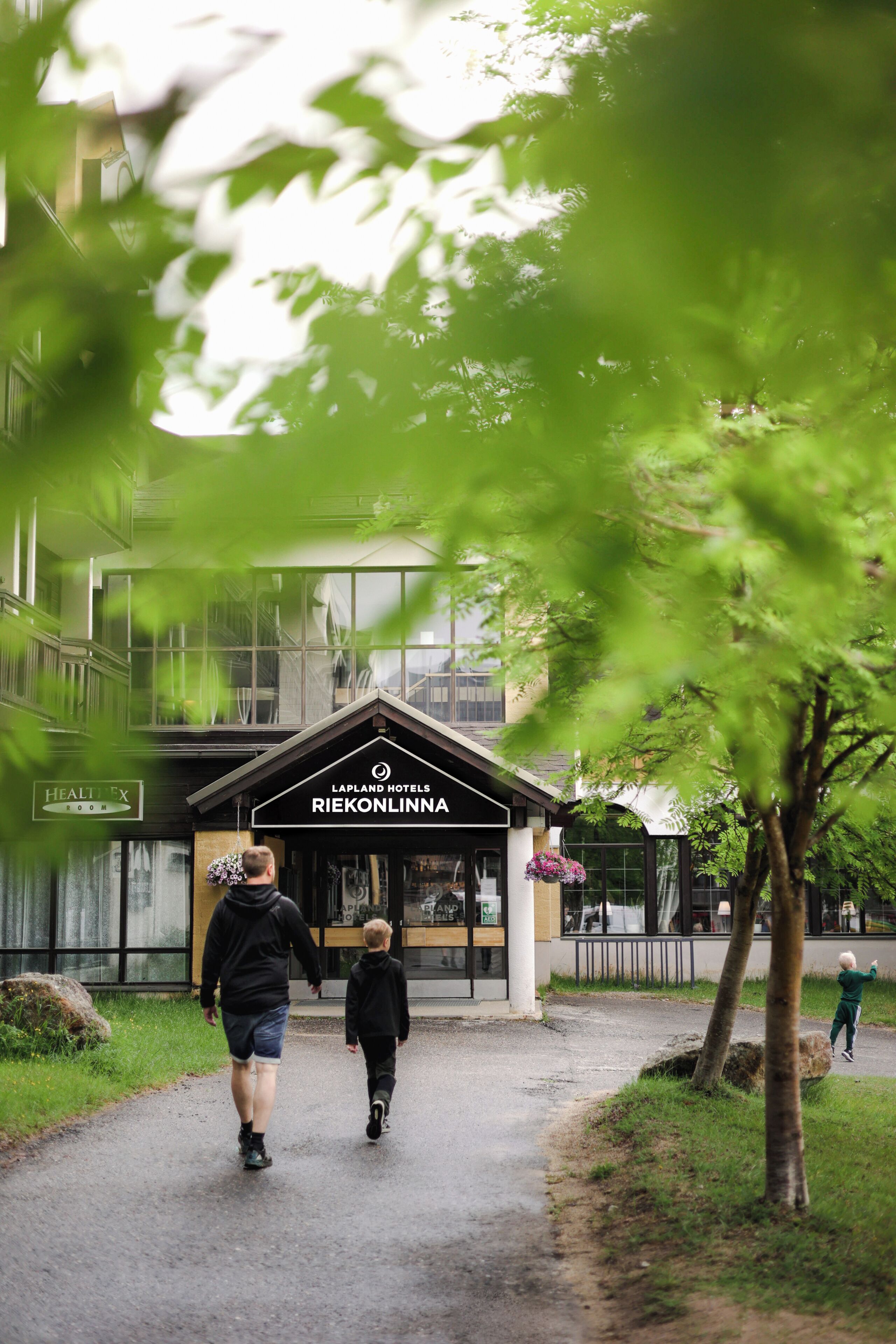 Ein Weg führt zu einem Hotel Eingang, an dem ein Schild 'RIEKONLINNA' steht.