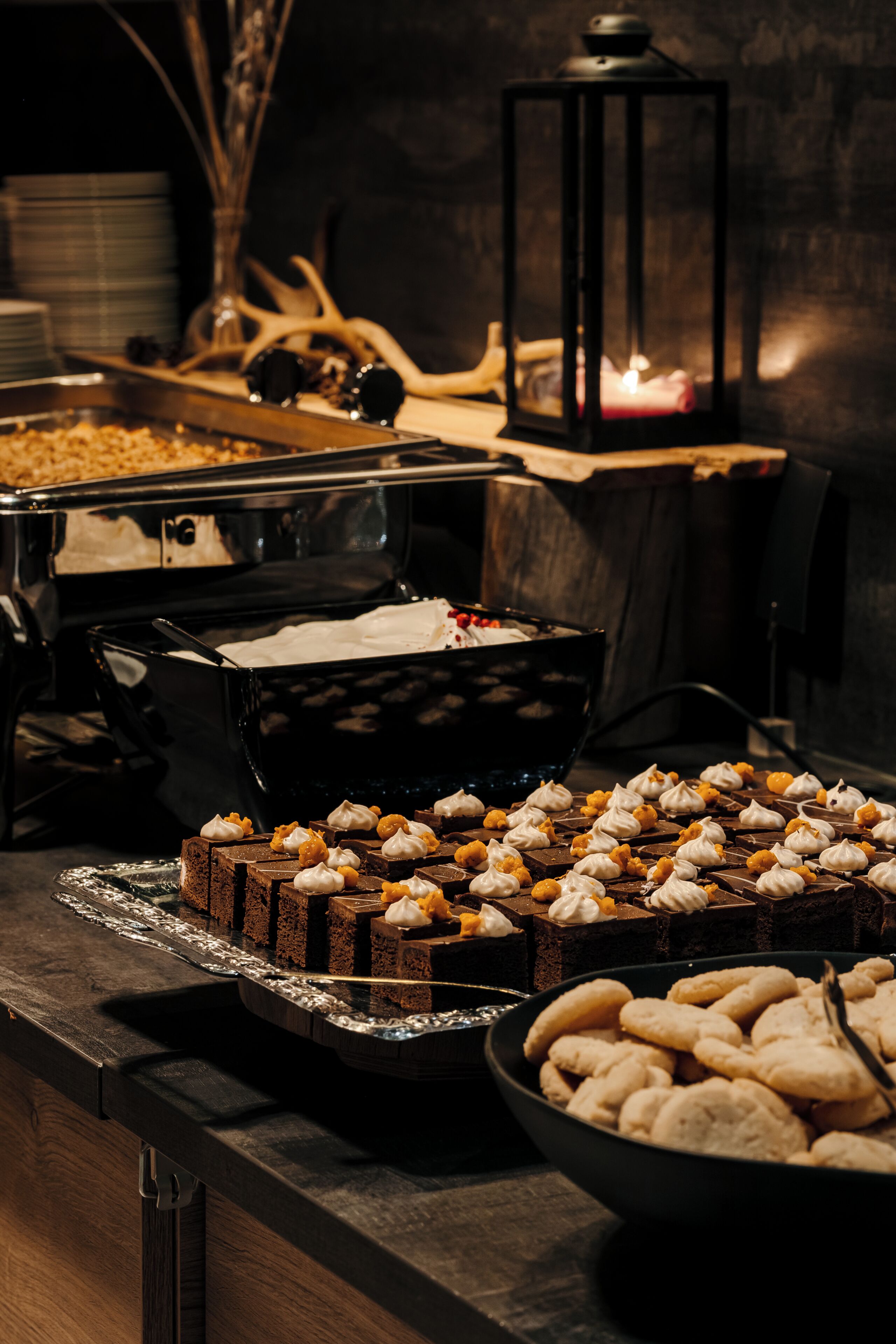 Une table de buffet garnie de divers desserts, avec une lanterne en arrière-plan.